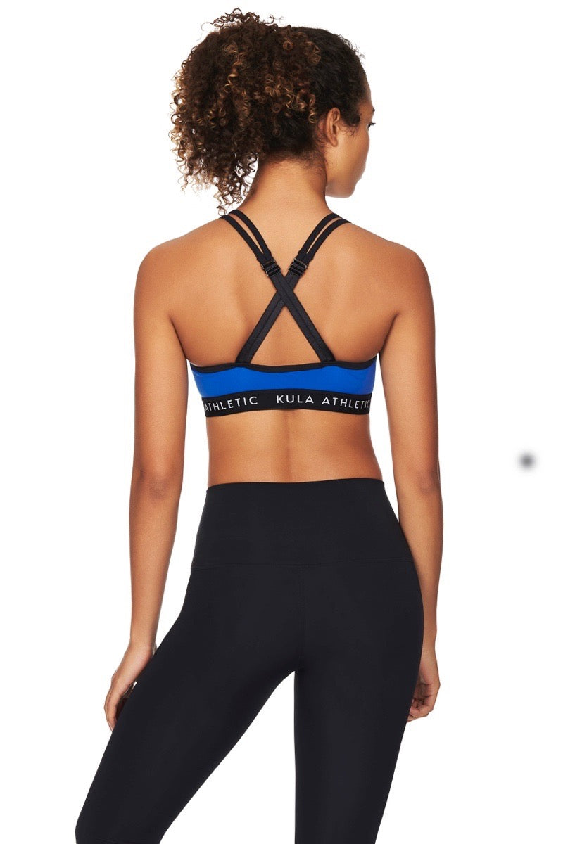 Back view of model wearing criss cross blue sports bra and black tights