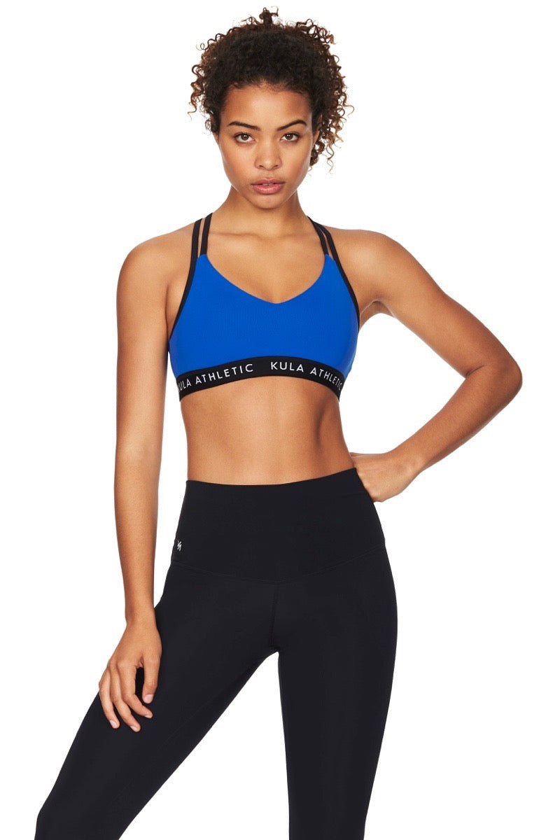 Model wearing a blue sports bra with black elastic waist band and black compression tights