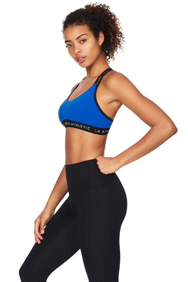 Side view of model wearing blue sports bra with black straps and black yoga pants