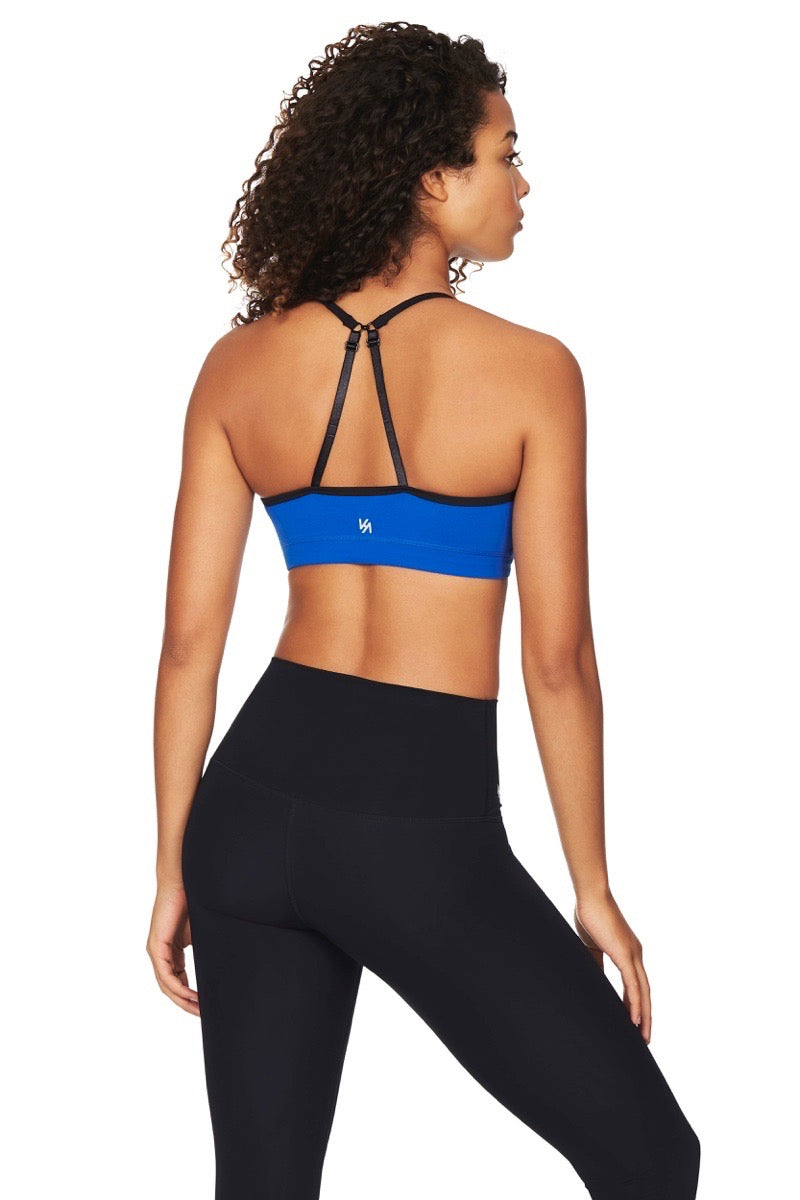 Women wearing blue sports bra with black straps and logo printed in white