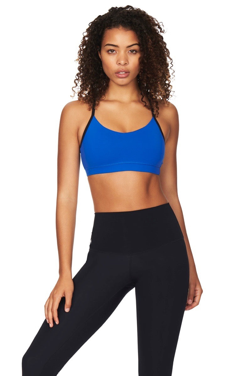 Women wearing blue sports bra with black straps and black yoga pants