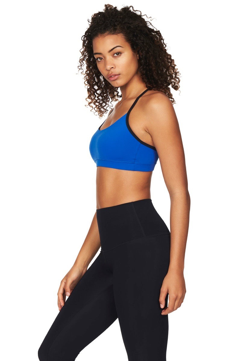Side view of model wearing blue sports bra with black straps and black leggings